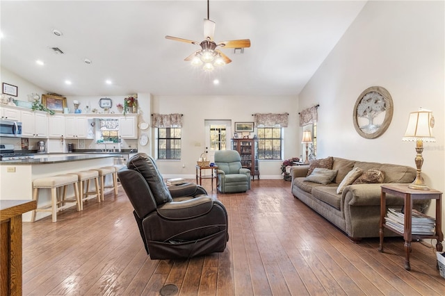 living room with vaulted ceiling, ceiling fan, and light wood-type flooring