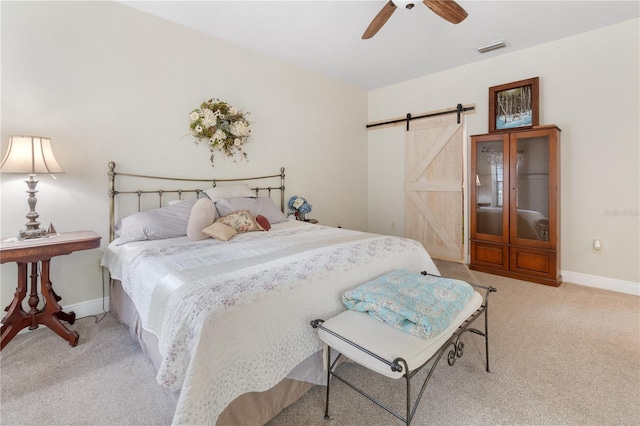 carpeted bedroom with a barn door and ceiling fan