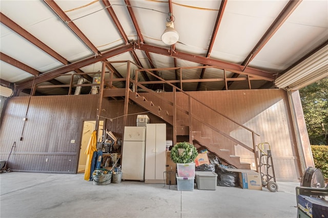 garage with white fridge and wooden walls