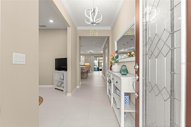 tiled foyer with ornamental molding and an inviting chandelier