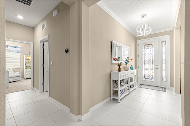 foyer featuring light tile patterned flooring, ornamental molding, a chandelier, and a textured ceiling