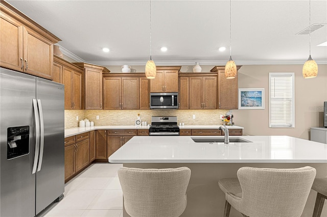 kitchen with sink, crown molding, hanging light fixtures, an island with sink, and stainless steel appliances