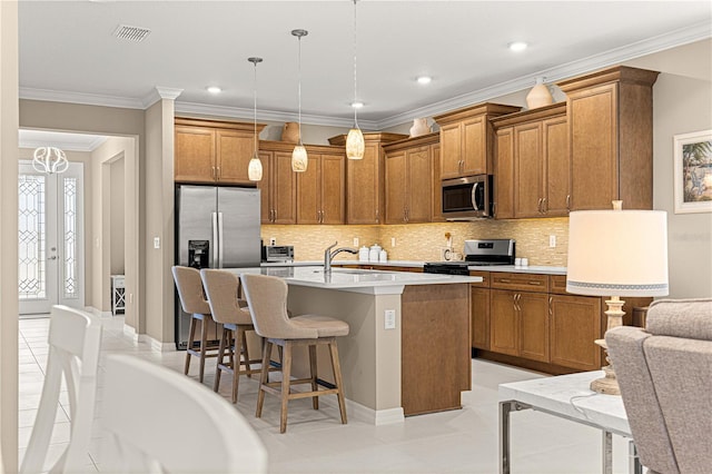 kitchen with sink, a breakfast bar, appliances with stainless steel finishes, an island with sink, and decorative light fixtures