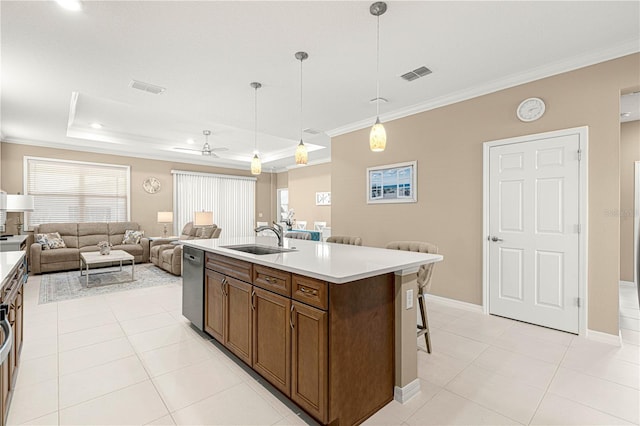 kitchen featuring sink, decorative light fixtures, ornamental molding, a tray ceiling, and a kitchen island with sink