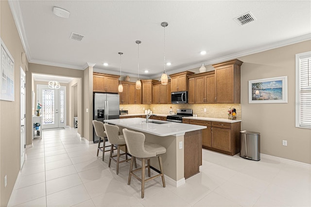 kitchen with crown molding, stainless steel appliances, a kitchen bar, and an island with sink