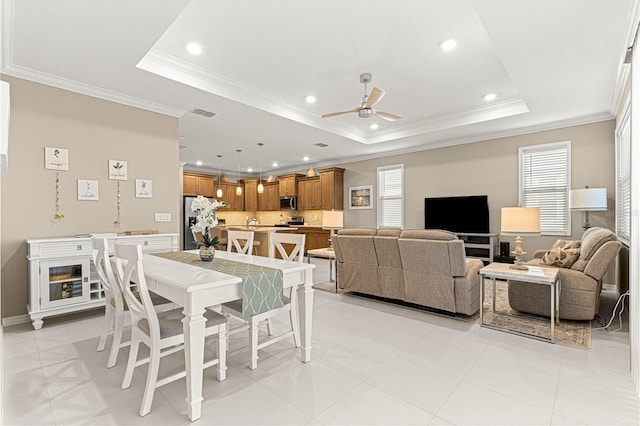 tiled dining area featuring crown molding, ceiling fan, and a tray ceiling