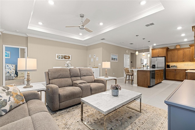 living room with a tray ceiling, ornamental molding, ceiling fan, and light tile patterned flooring