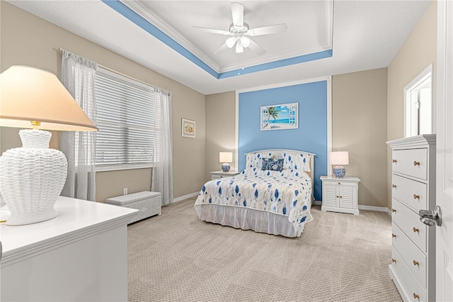 bedroom featuring ceiling fan, a tray ceiling, and light carpet