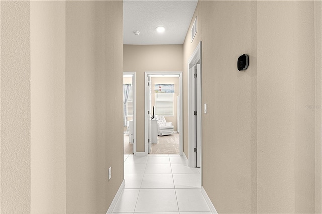 corridor featuring light tile patterned flooring and a textured ceiling