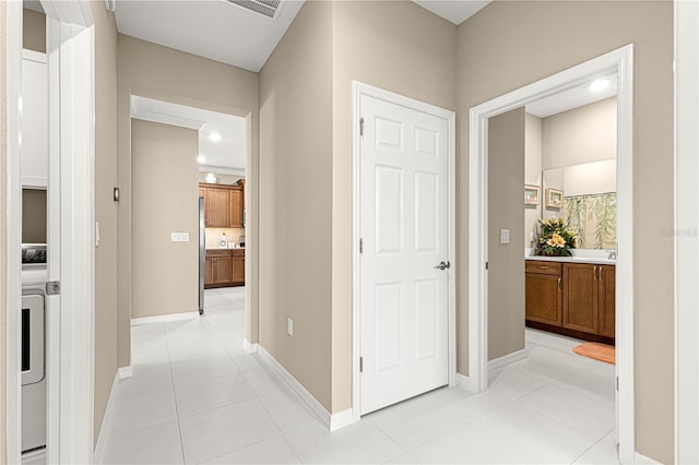 hallway featuring washer / clothes dryer, ornamental molding, and light tile patterned floors