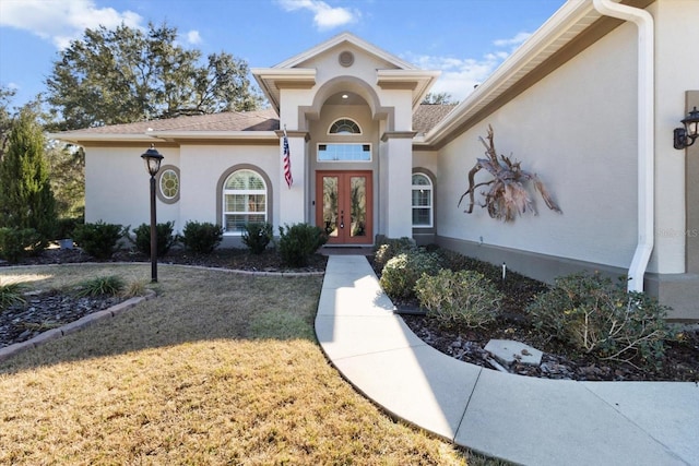 view of exterior entry featuring french doors and a yard