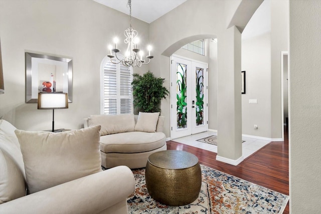 living room with french doors, wood-type flooring, high vaulted ceiling, and a notable chandelier