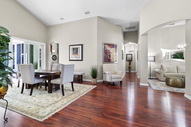 dining space with a high ceiling, dark hardwood / wood-style floors, and a chandelier