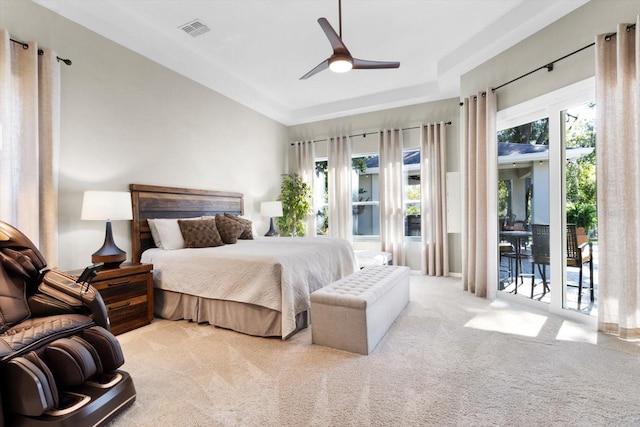 carpeted bedroom featuring multiple windows, a tray ceiling, access to outside, and ceiling fan