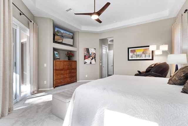 bedroom featuring a raised ceiling, light colored carpet, and ceiling fan