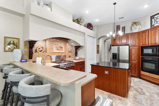 kitchen featuring pendant lighting, a kitchen breakfast bar, black appliances, decorative backsplash, and kitchen peninsula