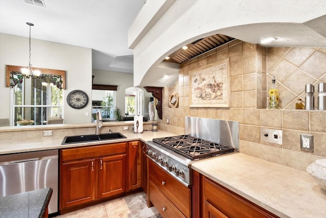 kitchen with sink, backsplash, stainless steel appliances, a notable chandelier, and decorative light fixtures