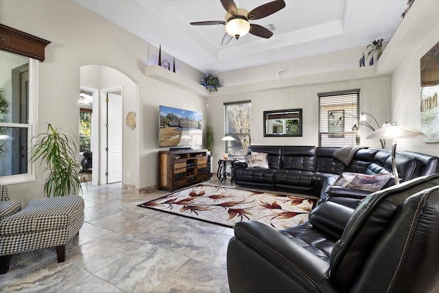 living room with ceiling fan and a tray ceiling