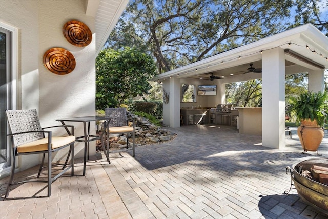 view of patio / terrace with ceiling fan, a grill, and exterior kitchen