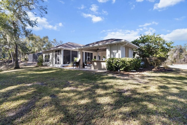 rear view of house with a lawn, a sunroom, and a patio