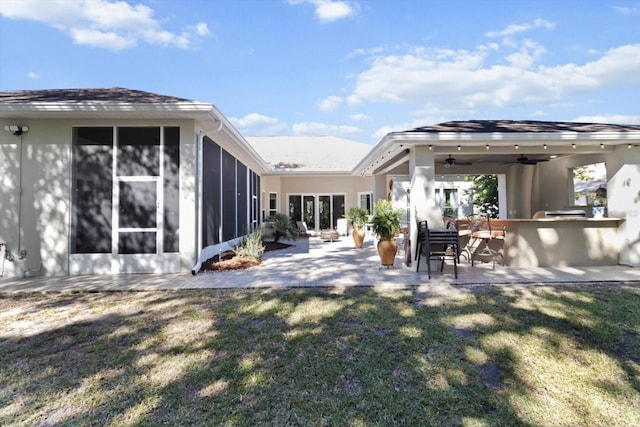 rear view of property featuring a lawn, ceiling fan, a patio, a sunroom, and area for grilling