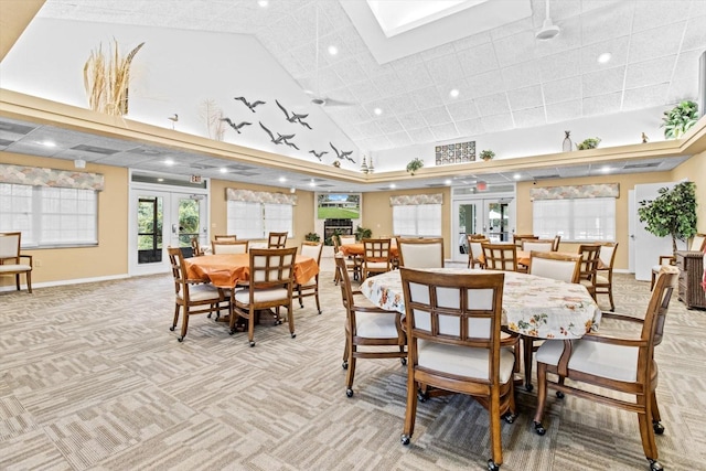 dining space with french doors, a skylight, high vaulted ceiling, and light carpet