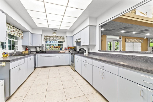 kitchen featuring sink, dishwasher, a healthy amount of sunlight, light tile patterned flooring, and stainless steel range with electric cooktop