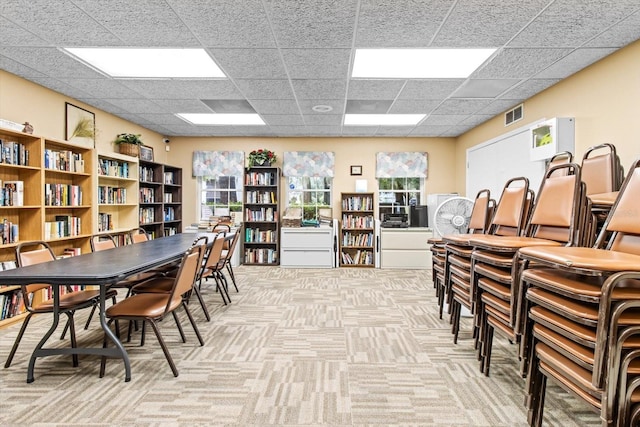 carpeted dining room featuring a drop ceiling