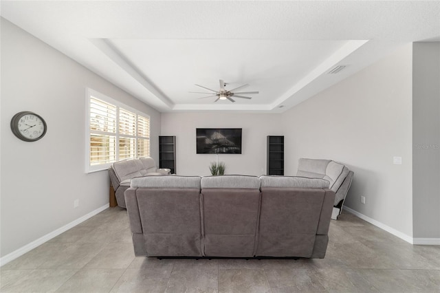 living room featuring a raised ceiling and ceiling fan