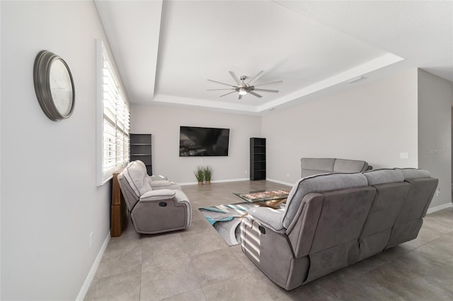 living room with ceiling fan and a tray ceiling