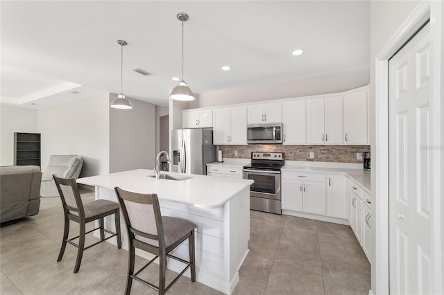 kitchen featuring sink, stainless steel appliances, white cabinets, and a center island with sink