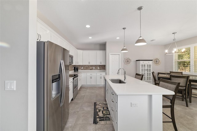 kitchen with white cabinetry, sink, a kitchen bar, stainless steel appliances, and a center island with sink