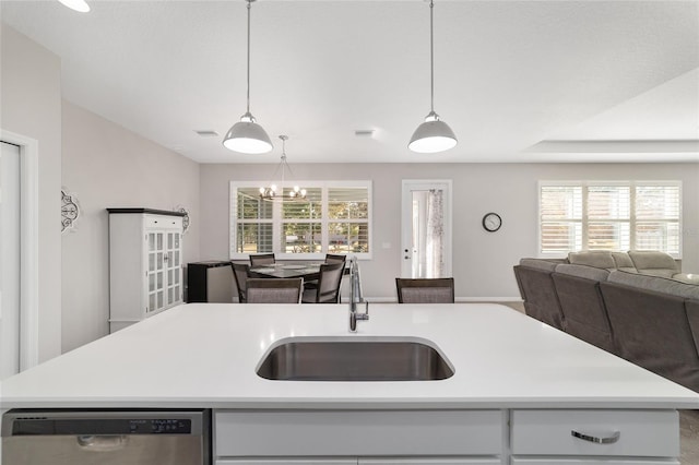 kitchen featuring decorative light fixtures, dishwasher, sink, and a center island with sink