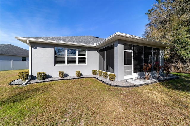 back of property with a lawn and a sunroom