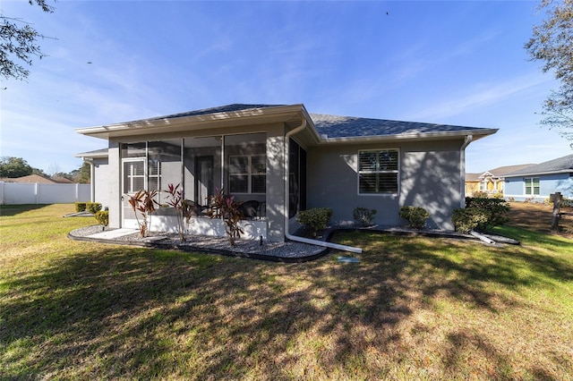 back of property with a lawn and a sunroom