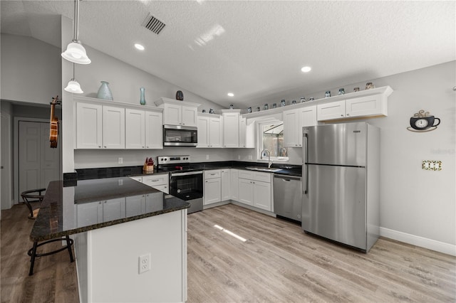 kitchen with white cabinetry, hanging light fixtures, vaulted ceiling, and stainless steel appliances