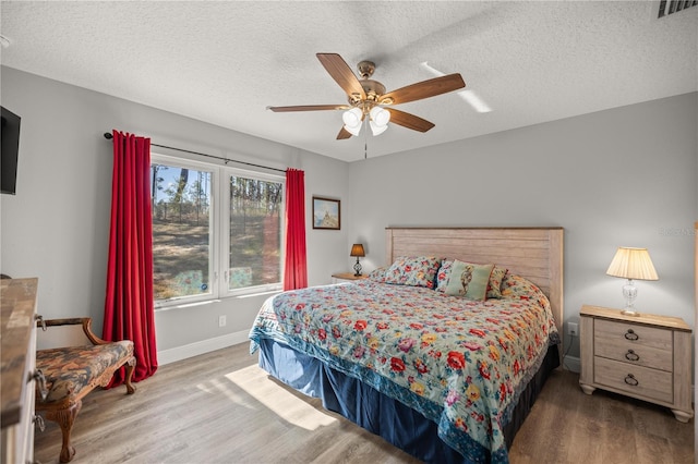 bedroom featuring hardwood / wood-style floors, a textured ceiling, and ceiling fan