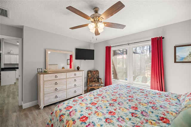 bedroom with a textured ceiling, ceiling fan, and light hardwood / wood-style flooring