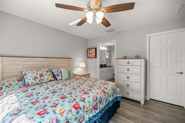 bedroom featuring ceiling fan, wood-type flooring, ensuite bath, and a textured ceiling