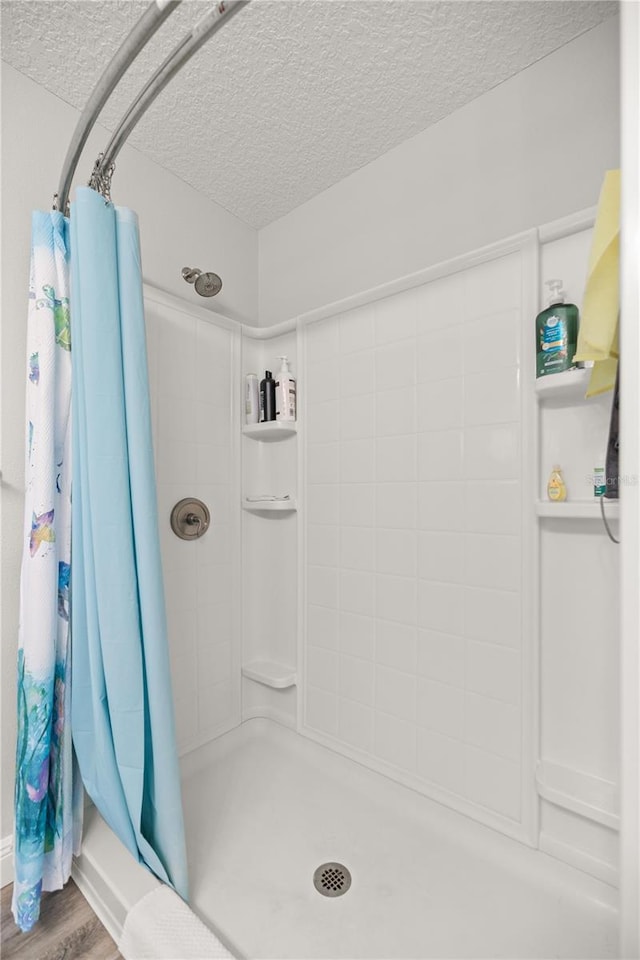 bathroom with hardwood / wood-style floors, curtained shower, and a textured ceiling