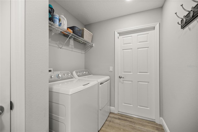 laundry area featuring independent washer and dryer, light hardwood / wood-style flooring, and a textured ceiling