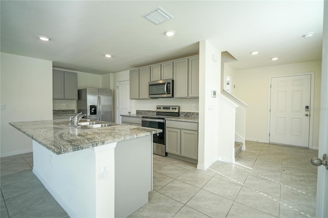 kitchen with sink, light tile patterned floors, gray cabinets, appliances with stainless steel finishes, and light stone countertops