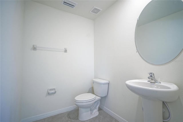 half bath featuring tile patterned floors, visible vents, baseboards, and toilet