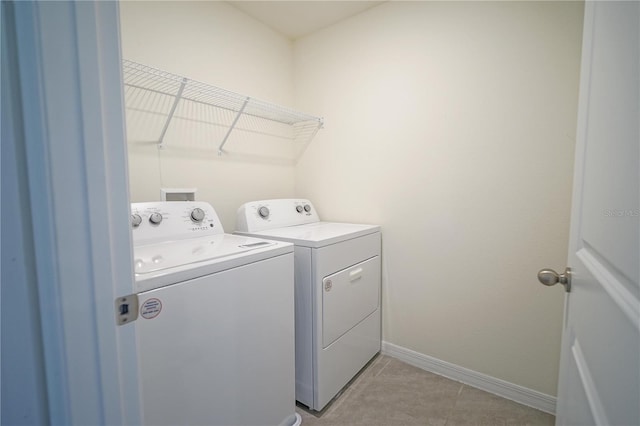 washroom with laundry area, light tile patterned floors, baseboards, and washing machine and clothes dryer