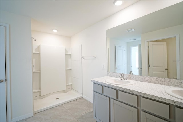 bathroom featuring double vanity, a shower, tile patterned floors, and a sink