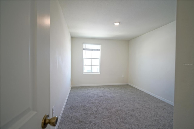 carpeted spare room featuring baseboards