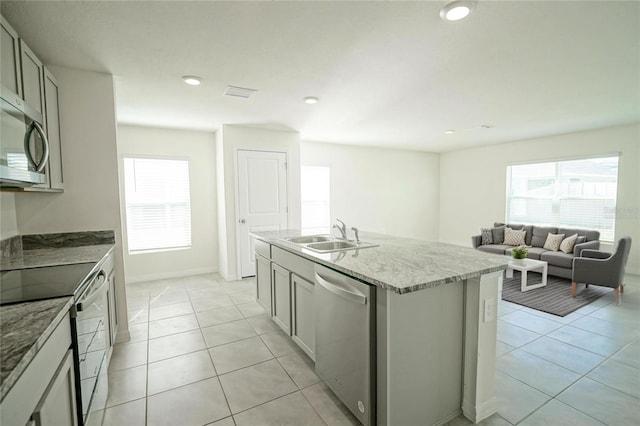 kitchen featuring a sink, plenty of natural light, appliances with stainless steel finishes, and light tile patterned flooring