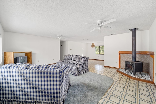 living room with ceiling fan, a textured ceiling, and a wood stove