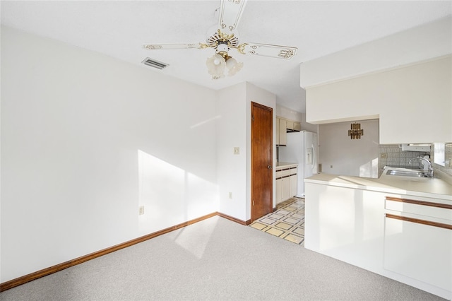 kitchen featuring sink, light carpet, white fridge with ice dispenser, ceiling fan, and decorative backsplash