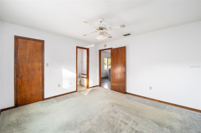 unfurnished bedroom with ceiling fan, connected bathroom, light colored carpet, and a textured ceiling